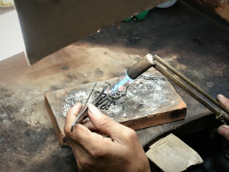 Manos de un joyero trabajando una pieza de oro en el taller